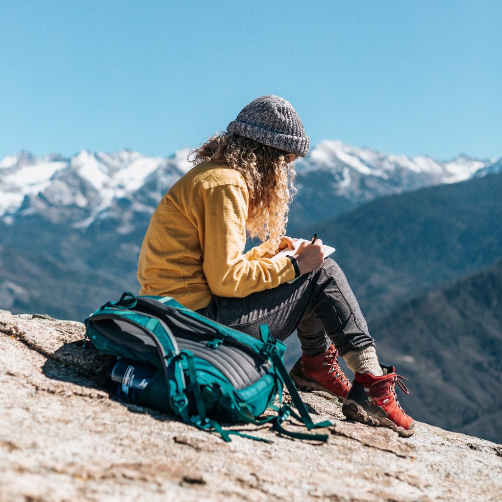 Woman journaling on a mountaintop